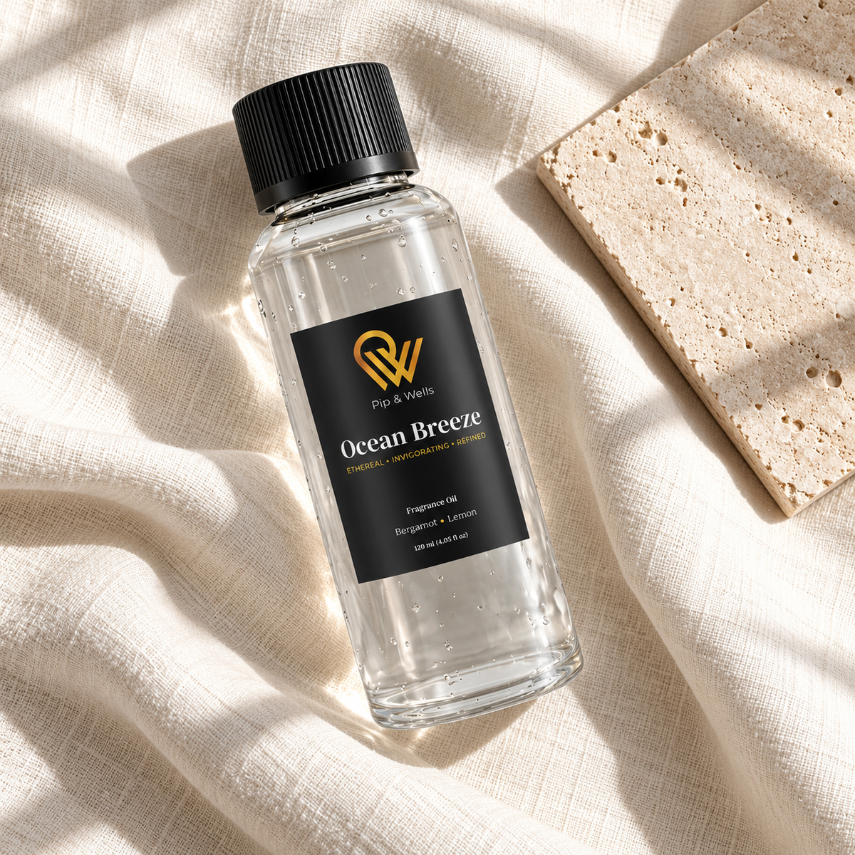 Frasco de aceite aromático Pip & Wells Ocean Breeze de 120 ml sobre lino claro, junto a una baldosa de piedra texturizada